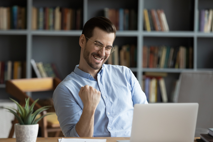 Excited man celebrating success, reading good news in email Excited man wearing glasses celebrating success, reading good news in email, happy overjoyed businessman looking at laptop screen, showing yes gesture and laughing, sitting at work desk