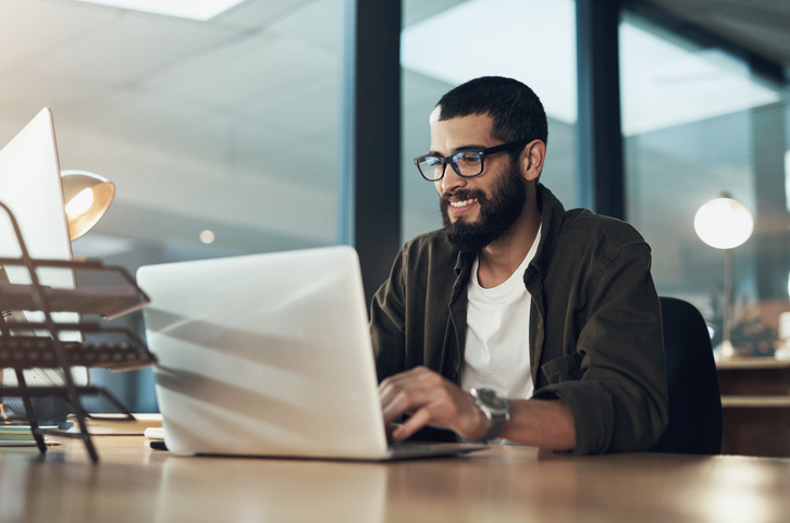 Put more in, get more out Shot of a young businessman using a laptop during a late night in a modern office