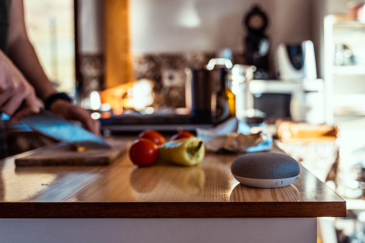 Smart home speaker with woman cooking in the background. Smart home AI device.